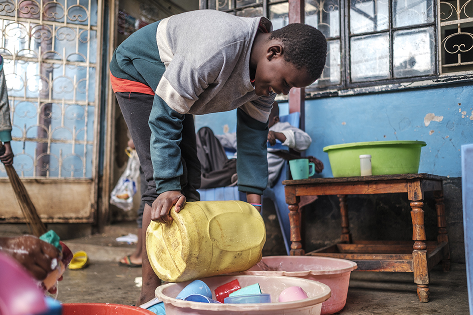 A youngster pours water from a jerrycan in order to wash dishes at the Kibera Pride Children’s Home, in the city of Nairobi, Kenya, on October 27, 2023.